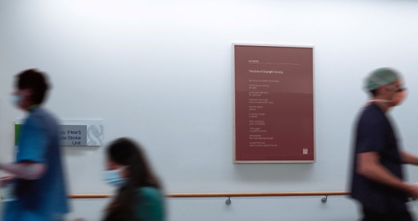 People rushing past a poem on a hospital wall