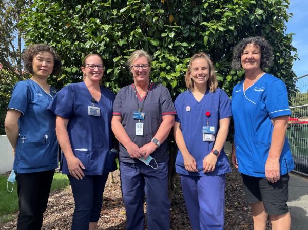 five nurses wearing blue uniforms.